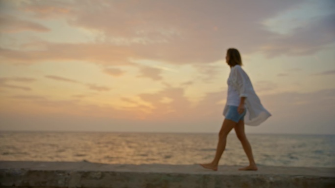 SLO MO海滨漫步:日落时码头上的女人的孤独漫步
