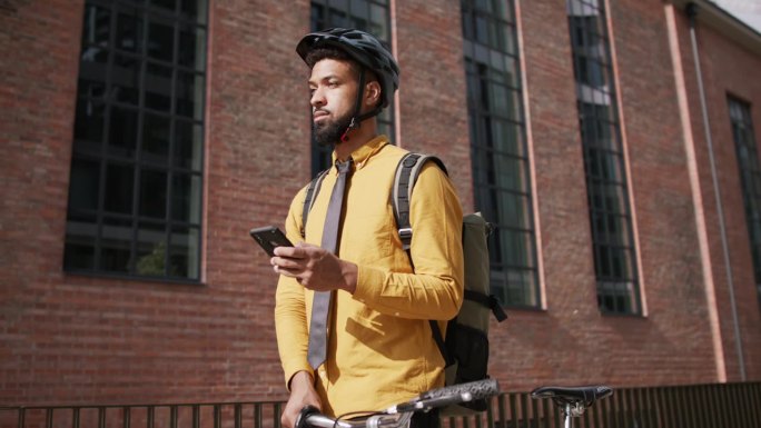 年轻人在城市里推着自行车和使用智能手机通勤。