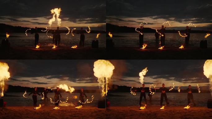 手持火把的特技演员在日落后的海滩上表演火焰表演，令人惊叹的慢镜头