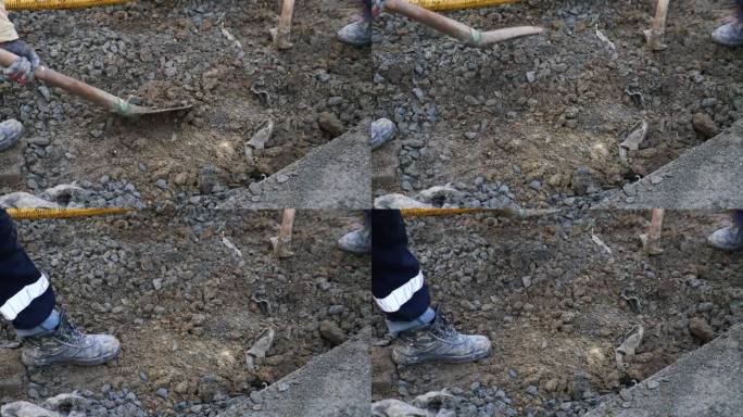 工人们用铲子把石头放进路上的坑里