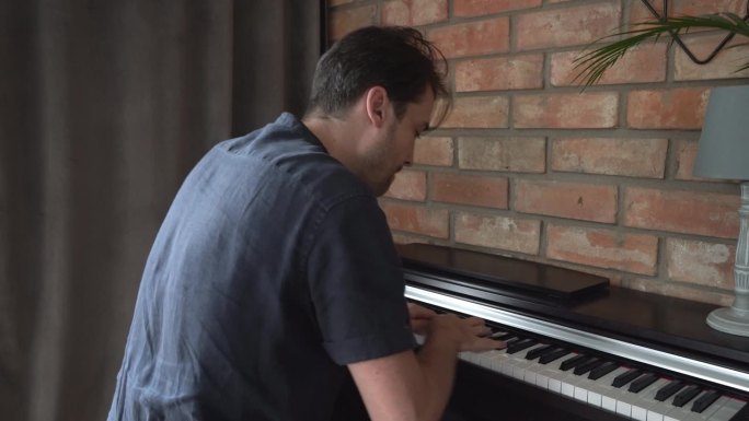 一位男钢琴家在家里弹奏数码电子钢琴