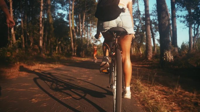 女子骑自行车，而朋友在乡间的路上玩滑板