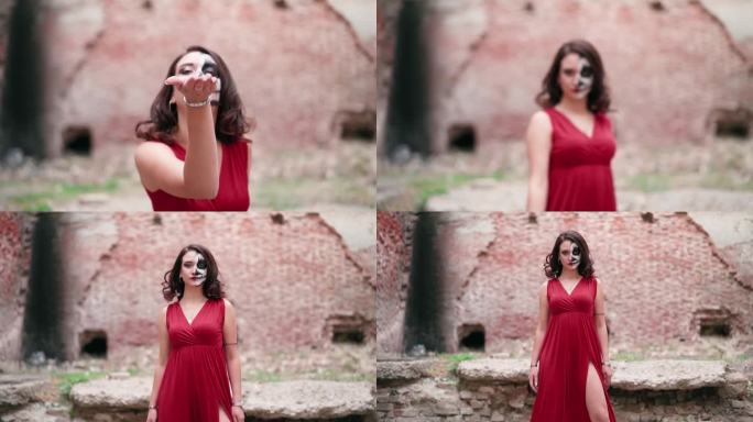 肖像女人在红色的衣服可怕的万圣节化妆站在废弃的建筑
