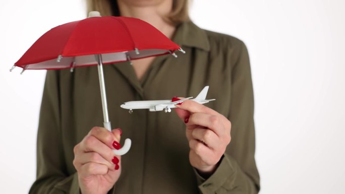 保险代理人手里拿着红色雨伞和玩具飞机