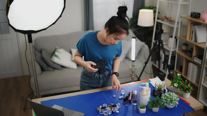 年轻的女摄影师在家庭摄影棚里整理产品