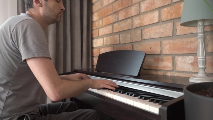 一位男钢琴家在家里弹奏数码电子钢琴