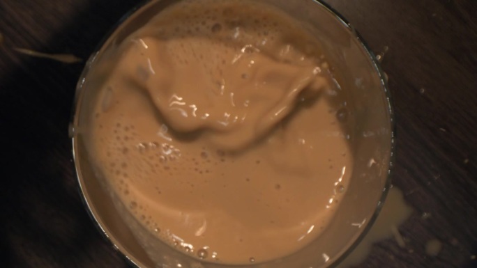 冷咖啡的宏观视角。慢镜头，一个女人往煮好的咖啡里扔冰块。冰块漂浮在咖啡表面。
