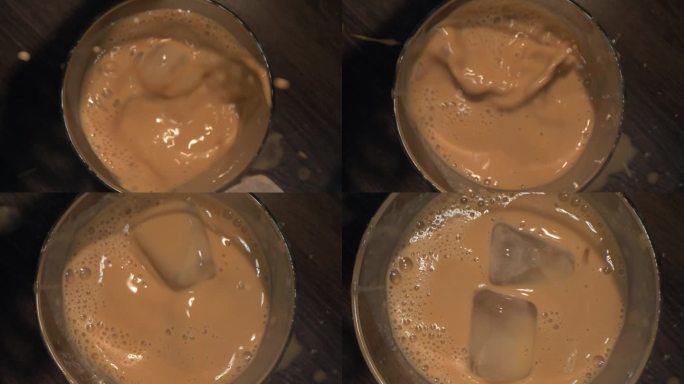 冷咖啡的宏观视角。慢镜头，一个女人往煮好的咖啡里扔冰块。冰块漂浮在咖啡表面。