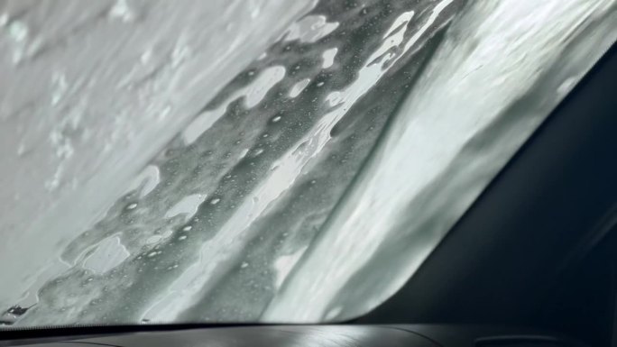 水流冲走了汽车挡风玻璃上的泡沫和污垢。