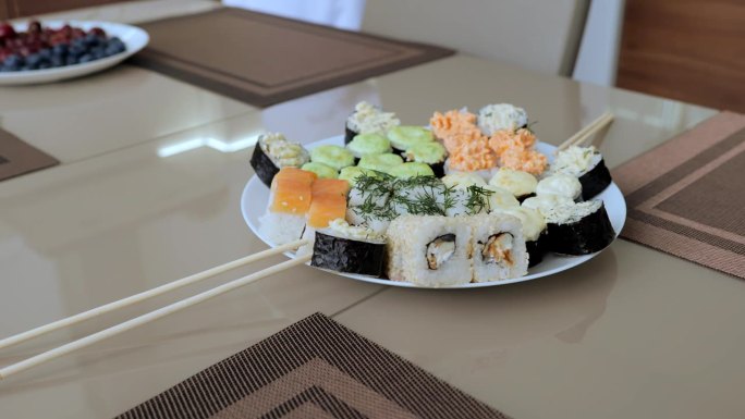 大量的食物种类和选择，以及寿司与水果和甜点。白色盘子里摆着各式各样的寿司。两个人的晚餐，有寿司和红酒