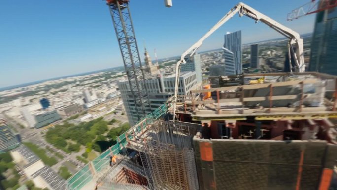 FPV无人机飞行视图的一个高大的现代商业大厦施工现场与施工起重机