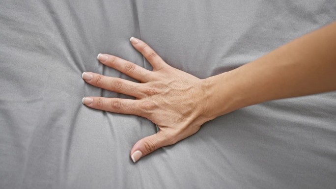 激情的亲密表达，女人的手，在舒适的卧室床上上升的高潮