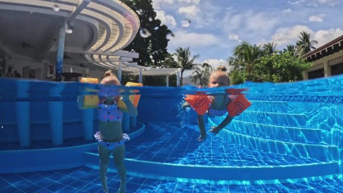 两个小女孩戴着通气管在游泳池里游泳