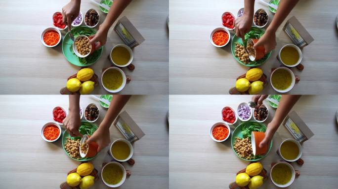 加入鹰嘴豆制作沙拉的航拍图，加入番茄胡萝卜菠菜鹰嘴豆柠檬洋葱坚果调味汁