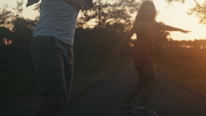 一对夫妇在路上玩滑板的剪影