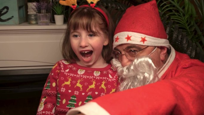 圣诞老人给小女孩看了一样东西，小女孩惊喜地看着