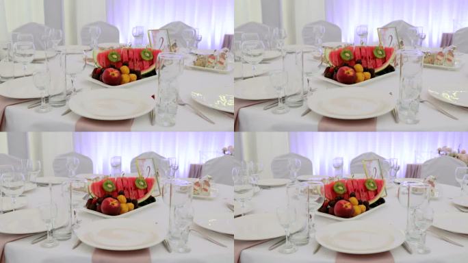 豪华餐厅里优雅的餐桌摆设。为正式仪式准备的豪华宴会桌。没有食物的圆桌上有盘子、餐巾、玻璃杯和餐具。