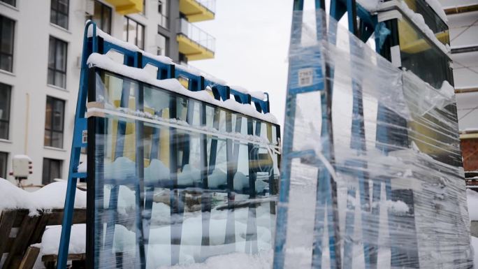 在建住宅楼。一个未安装的双层玻璃窗在冬季被包装并包裹在室外的薄膜中