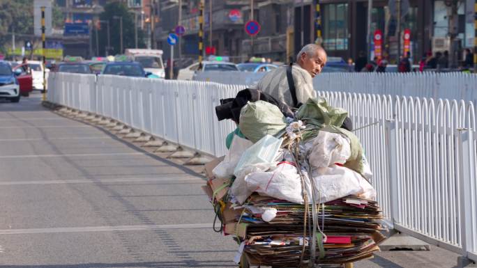 在大街上拖着一车纸皮垃圾的老人