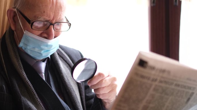 一位年长的白人老人爷爷坐在自助餐厅里看报纸。