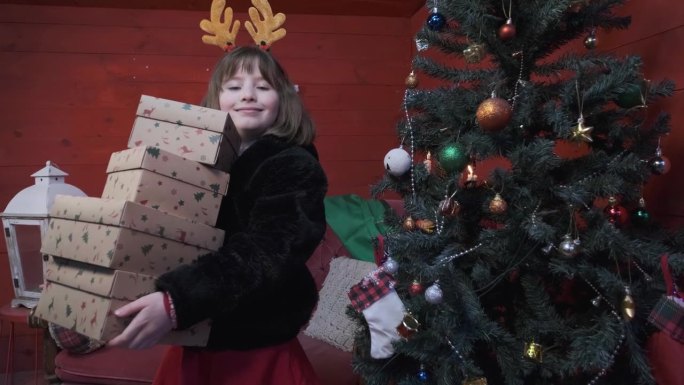 可爱的小女孩抱着新年礼物快乐地站在圣诞树旁
