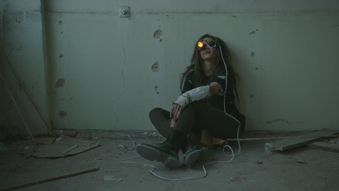 疯狂的发明家测试手工VR眼镜。疯狂的女科学家穿着脏衣服坐在破旧的房间里测试发明的虚拟现实眼镜，上面闪