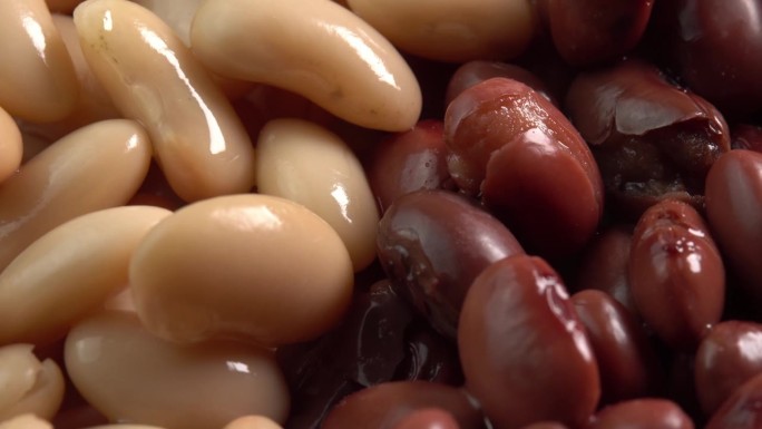 红芸豆和白芸豆罐头旋转背景微距低光。有机蒸豆。墨西哥菜的腌豆