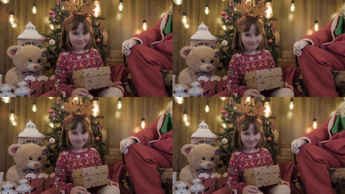 小女孩在大圣诞树前从圣诞老人那里收到她的圣诞礼物