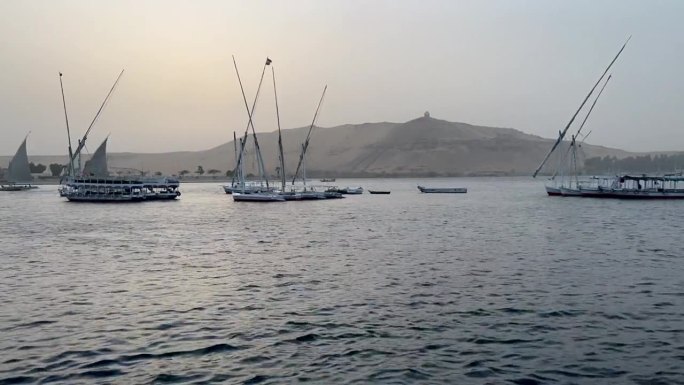 埃及阿斯旺的象岛。日落时分，三桅帆船和船只在埃及的尼罗河上穿行，阿斯旺的大象岛尽收眼底。埃及的景观。
