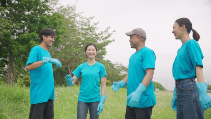 志愿、慈善和清洁环境的理念。快乐的亚洲志愿者在清扫公园、路边、复印空间之后或之前把手放在一起。4 k