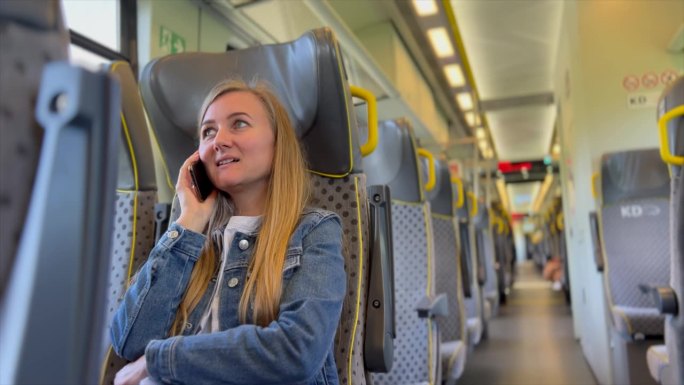 一名妇女在地铁上打电话，一名乘客坐在地铁座位上。