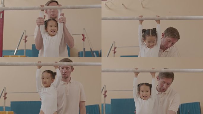 男教练帮助体操小女孩在杠上做引体向上