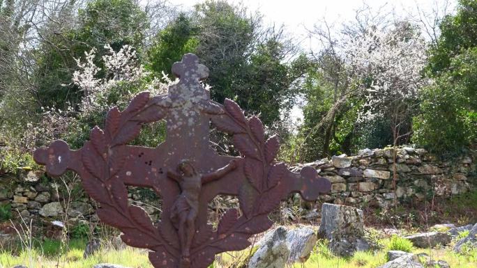 在一个温暖的春日下午，古老的爱尔兰饥荒公墓的金属十字架矗立在一座破旧的教堂中间