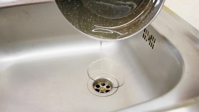 将废油倒在排水管上的微距镜头。收集使用过的家用食用油。