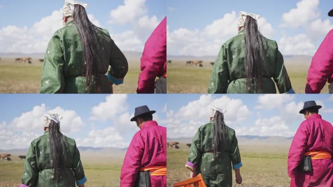 一对蒙古夫妇扛着桶穿过牧场去挤牛奶