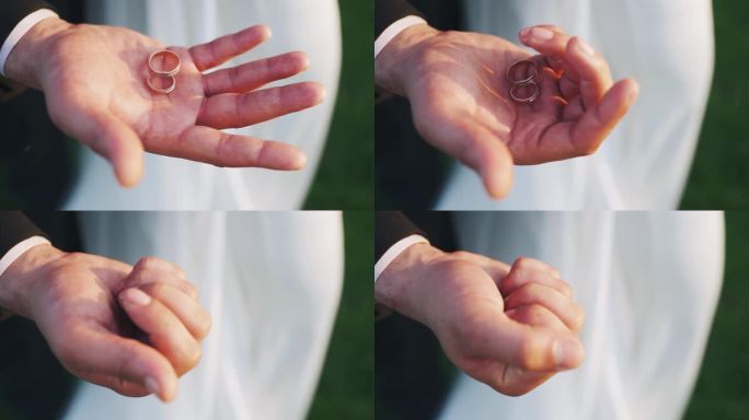 男人手里拿着结婚戒指。手掌捏着两个结婚戒指。爱的象征。新郎拿着戒指。