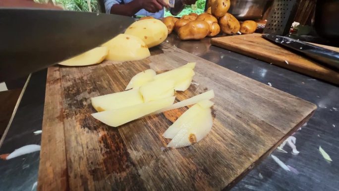 手拿刀在厨房的木板上切土豆。健康的饮食和生活方式。