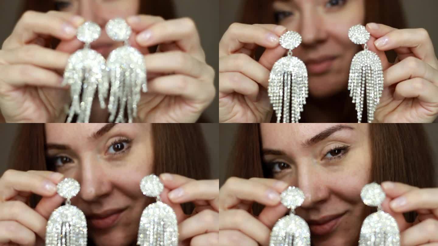 一个戴着大耳环的女人的特写。女孩戴着奢华昂贵的珠宝，上面有闪闪发光的钻石和宝石。女性双手紧握，露出耳