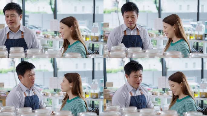快乐的男店主为穿着绿色休闲服装的亚洲女性顾客推荐合适的产品，她正在寻找有机产品来支持她健康和可持续的