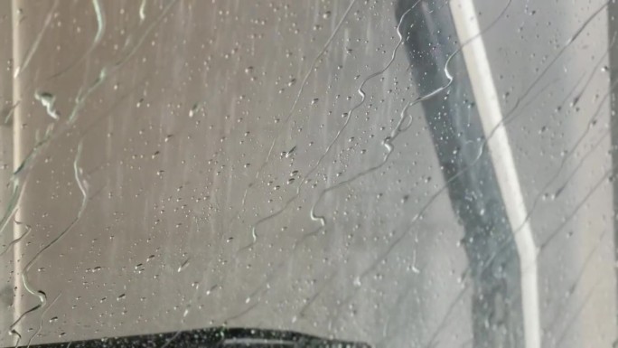 水珠自然落在玻璃上，风挡玻璃上有凝露，强度大，湿度高，大水珠顺着车窗流下，色调冷峻。