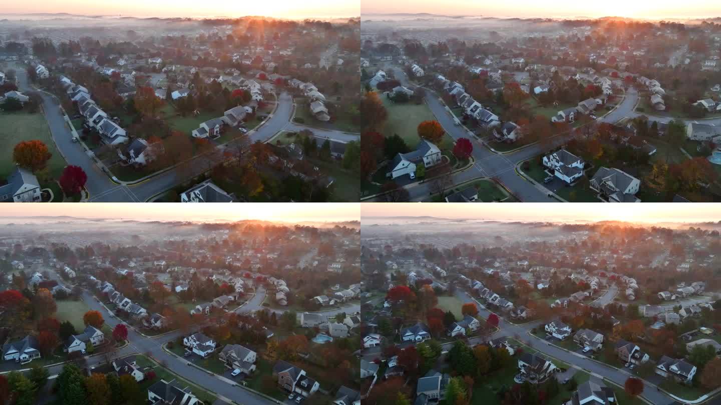 美国的一个社区，秋天日出时雾气笼罩着两层住宅。空中展示的大郊区与色彩缤纷的秋叶。