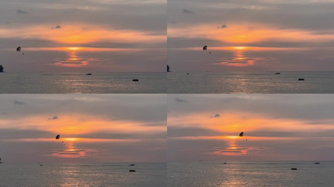 泰国海岸上的夕阳，沙滩上的娱乐活动——摩托艇后面的降落伞，人们在海面上跳伞