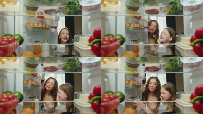妇女和女孩用健康食品打开冰箱门并服用产品。快乐家庭做饭和选择冰箱食材。微笑的人们选择储存食物的生活