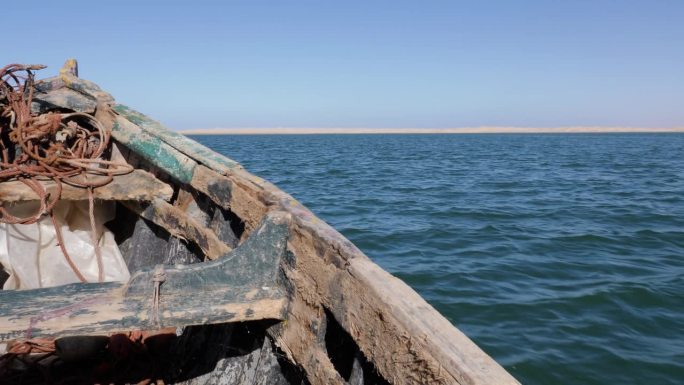 一只饱经风霜的旧捕鱼靴驶向拉克奈拉的沙丘。撒哈拉沙漠与大西洋的交汇处，拉克奈拉，摩洛哥肯尼菲斯国家公