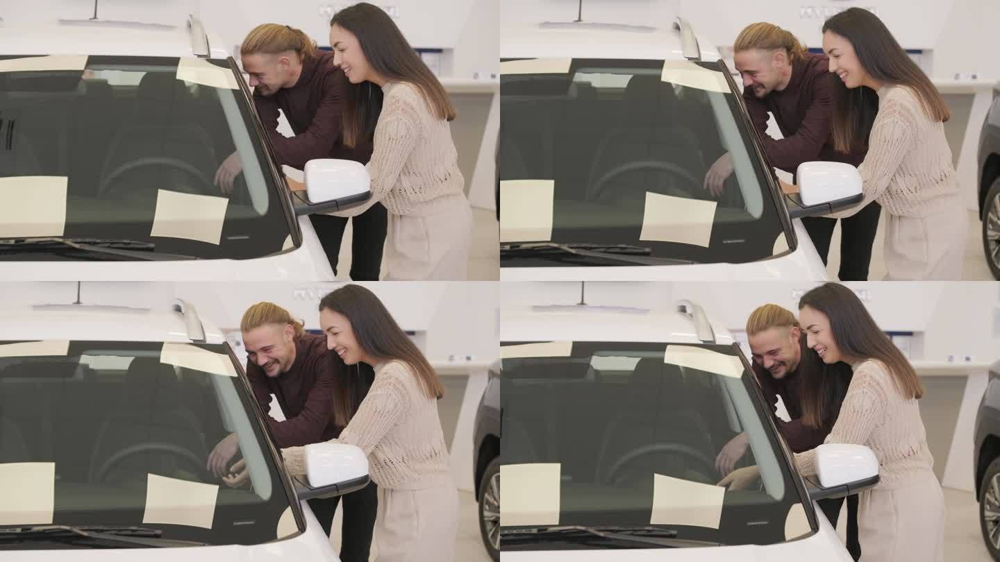 漂亮的年轻夫妇在汽车展示厅挑选新车。