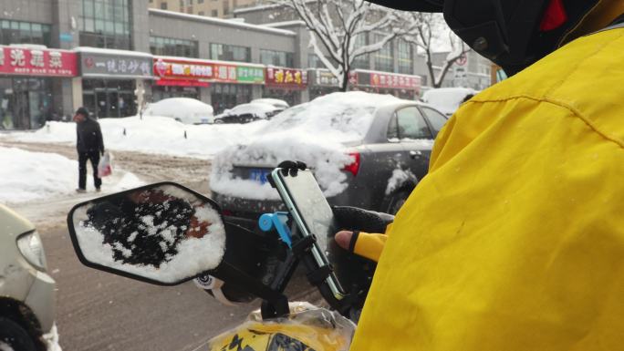 雨雪天外卖骑手取餐送餐在马路上骑行看手机