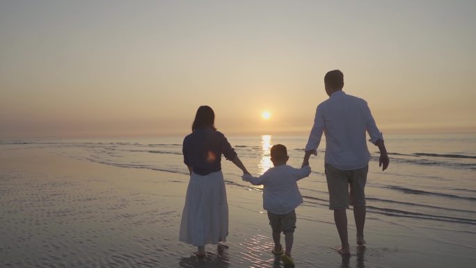 一家三口手拉手沙滩漫步背影温馨家庭幸福