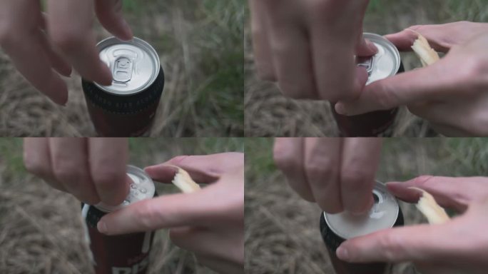 站在草地上的女人的手打开了一罐啤酒。从上方的侧视图。泡沫超出了罐子的边缘。
