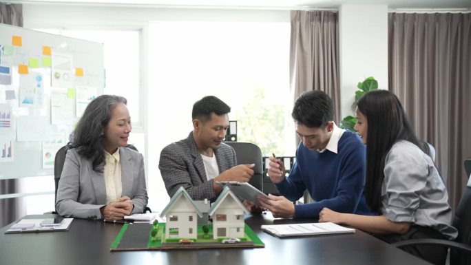 房地产经纪人正在讲解房屋模型查看房屋平面图和买卖合同，房屋买卖合同的条件，与客户合法签订合同。