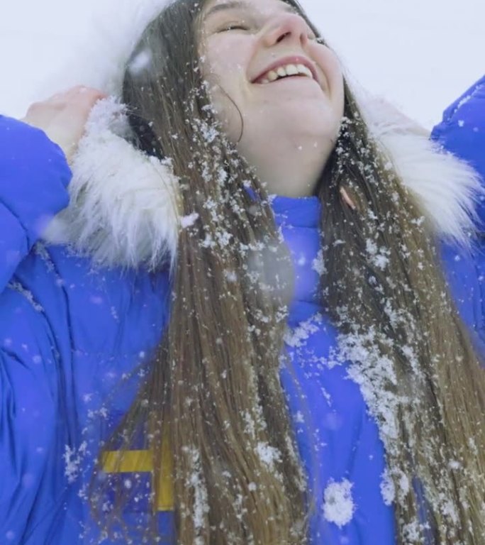 穿着蓝色外套的女人欣赏真正的冬季童话，在大雪中漫步在斯堪的纳维亚村庄